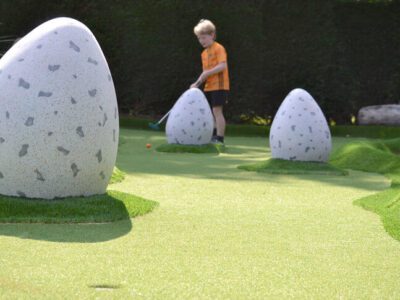 little boy playing mini golf