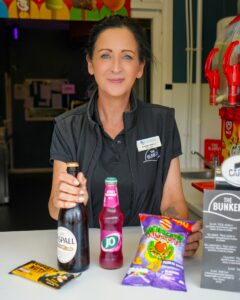 Staff member at The Bunker café counter presenting drinks and snacks including Aspall cider