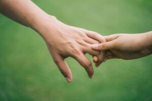 Two people holding hands on a green background